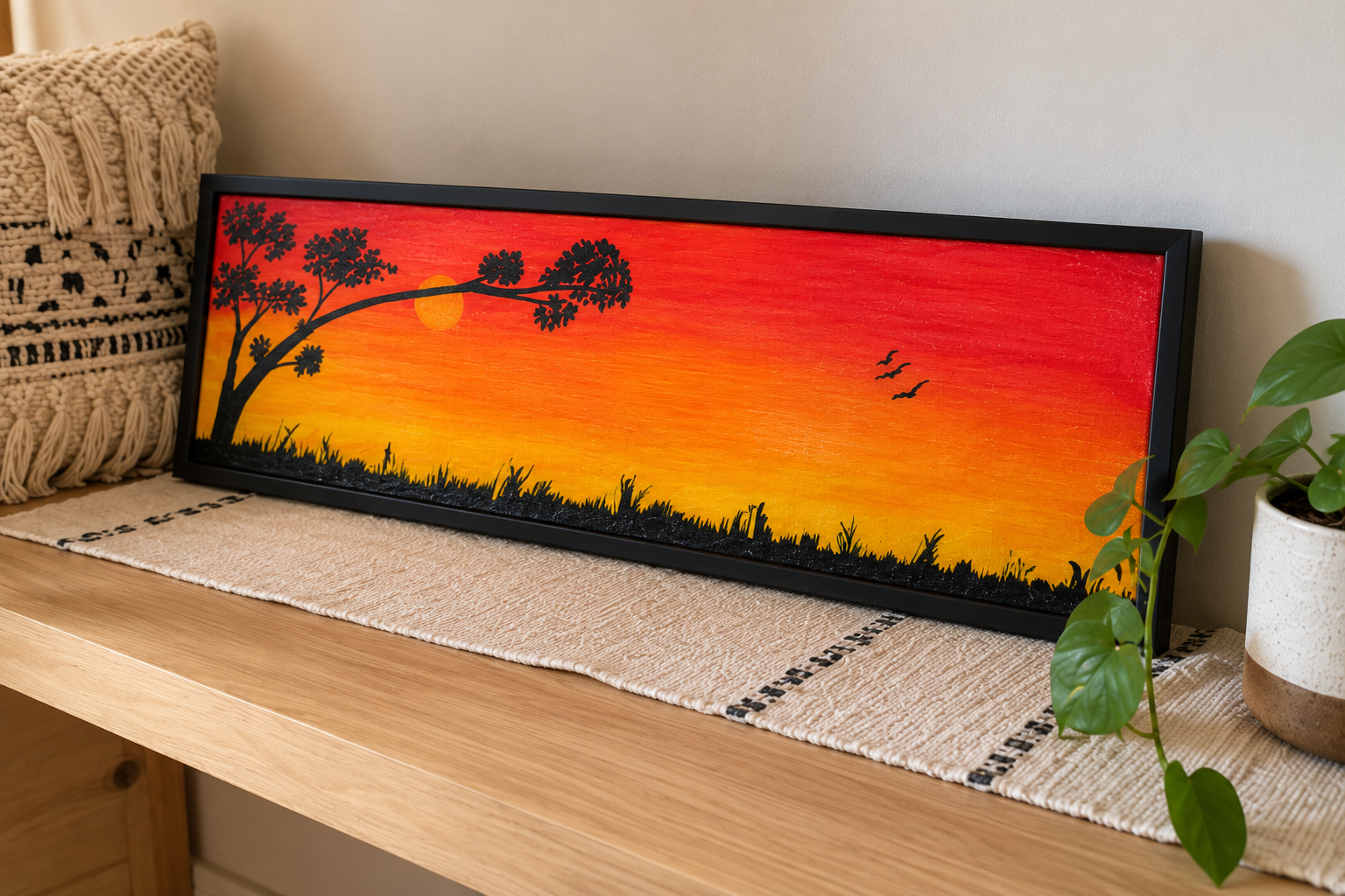 Golden Hour, a panoramic sunset painting in a black frame, displayed on a console table